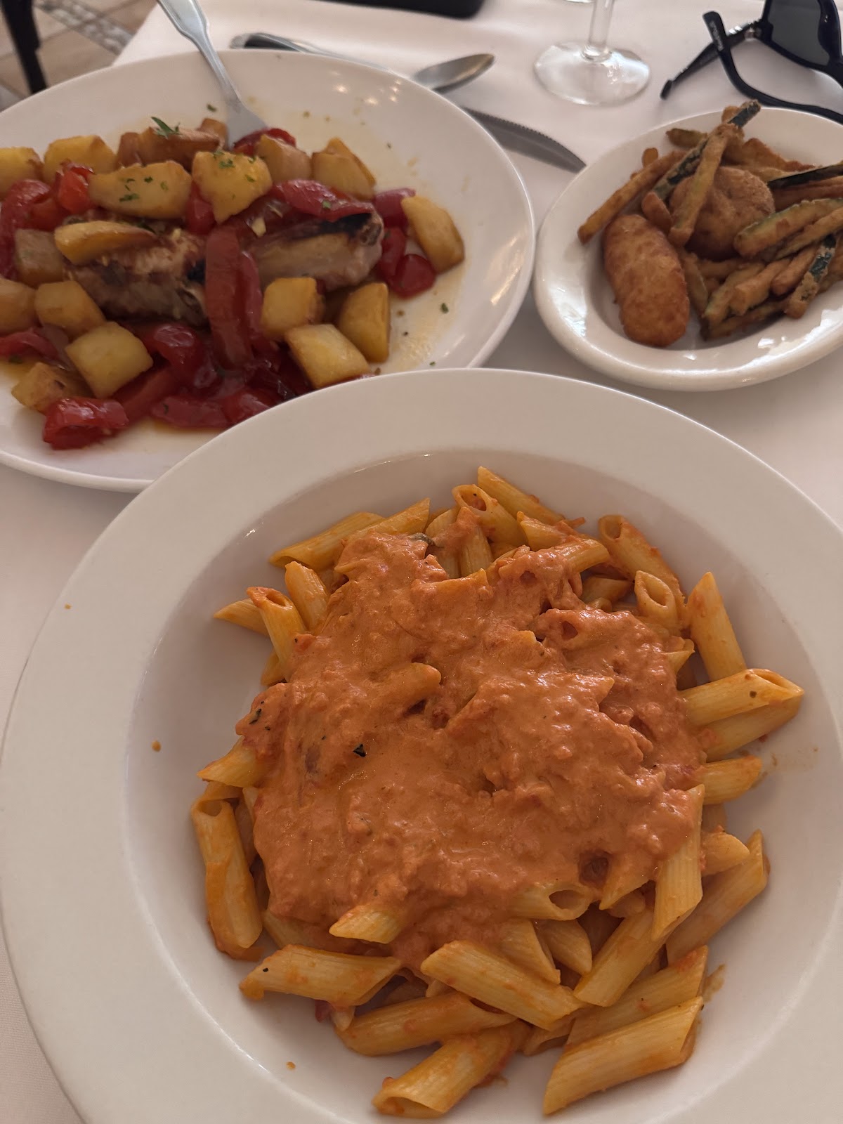 A table set with penne alla vodka, sausage and peppers, fried zucchini